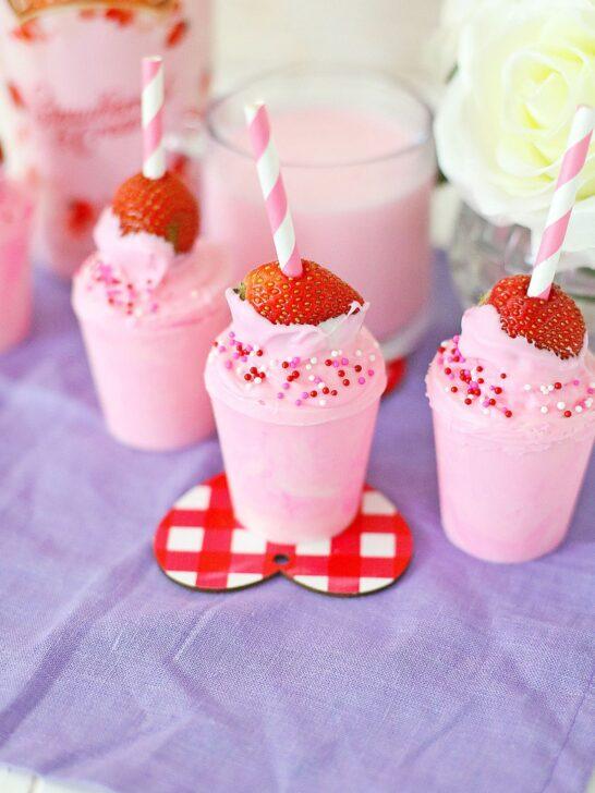 A Valentine's Day treat, a pink milkshake with straws and sprinkles.