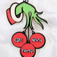 A Grinch wood ornament handily holds three red baubles labeled