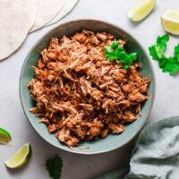 Instant Pot Mexican Carnitas in a blue bowl with tortillas