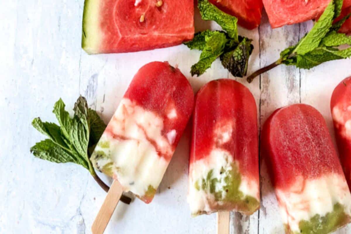 Homemade watermelon and mint popsicles on a wooden surface, showing vibrant red and green colors with visible chunks of fruit, make for tempting desserts.