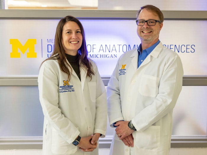 two scientists next to eachother smiling at camera white coats