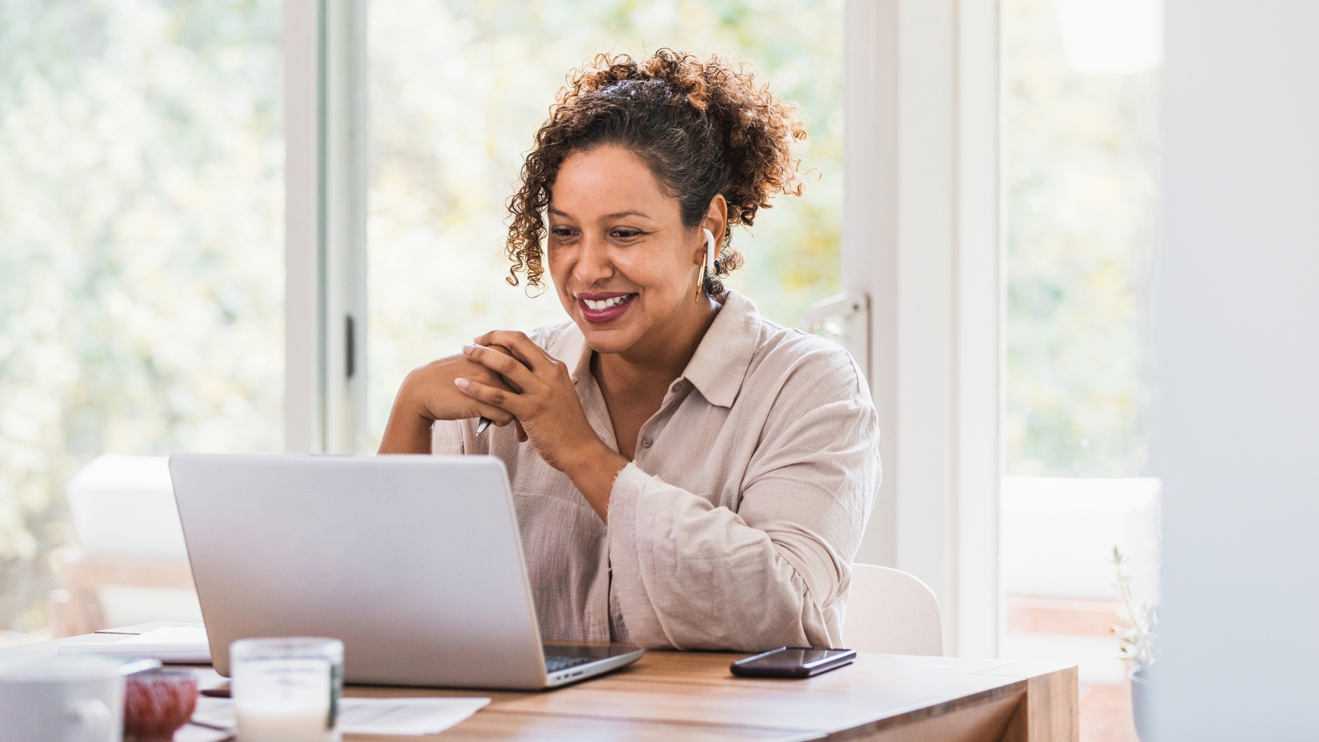 woman wearing headphone smiling at laptop sitting at desk 