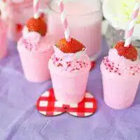 A Valentine's Day treat, a pink milkshake with straws and sprinkles.